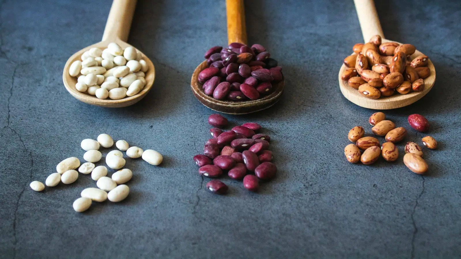 Wooden spoons of white, red and brown beans